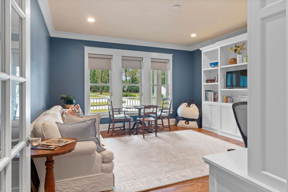Cette photo montre un grand bureau bord de mer avec une bibliothèque ou un coin lecture, un mur bleu, un sol en vinyl, un bureau intégré et un sol marron.
