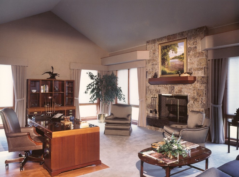 Modelo de despacho tradicional con paredes grises, todas las chimeneas, marco de chimenea de piedra y escritorio independiente