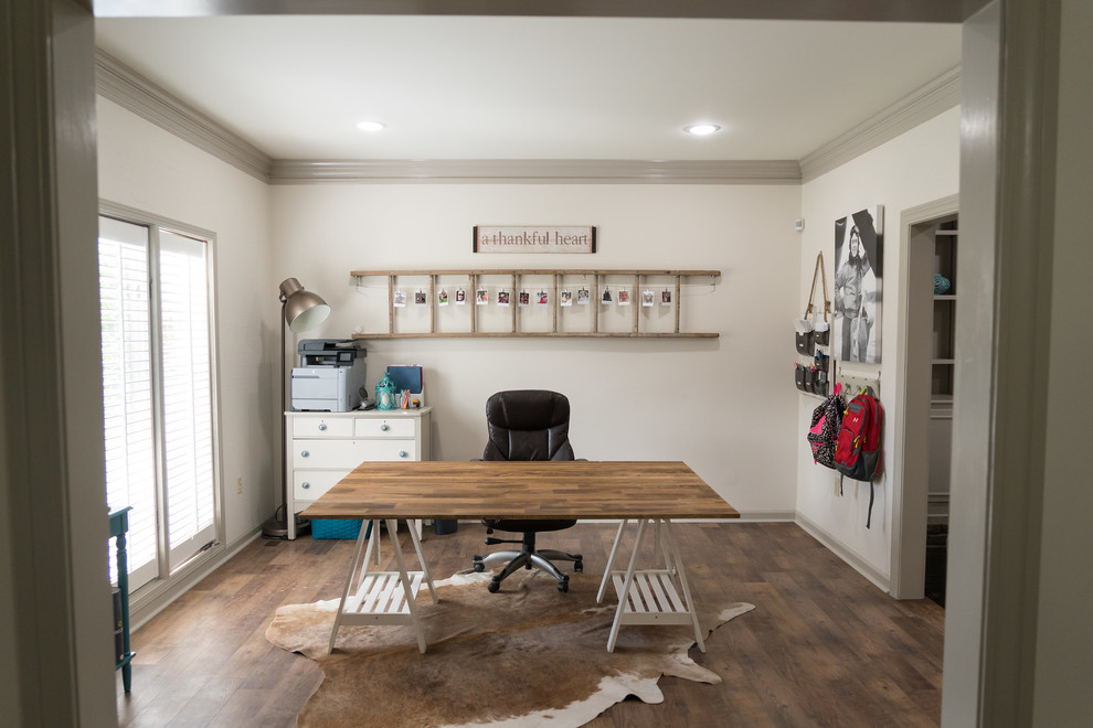 Modelo de despacho tradicional renovado de tamaño medio sin chimenea con paredes blancas, suelo vinílico, escritorio independiente y suelo marrón