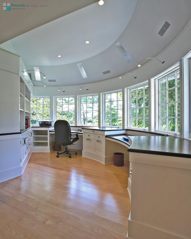 Aménagement d'un bureau classique avec un mur blanc, parquet clair et un bureau intégré.