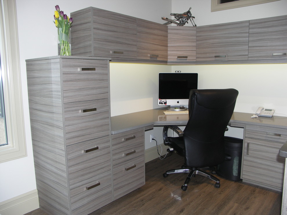 Mittelgroßes Modernes Arbeitszimmer ohne Kamin mit Arbeitsplatz, weißer Wandfarbe, braunem Holzboden, Einbau-Schreibtisch und braunem Boden in Calgary