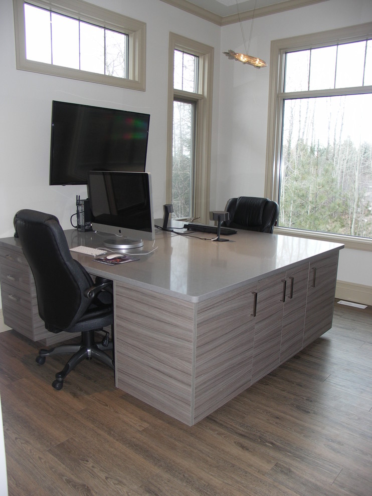 Ejemplo de despacho contemporáneo de tamaño medio sin chimenea con paredes blancas, suelo de madera en tonos medios, escritorio empotrado y suelo marrón