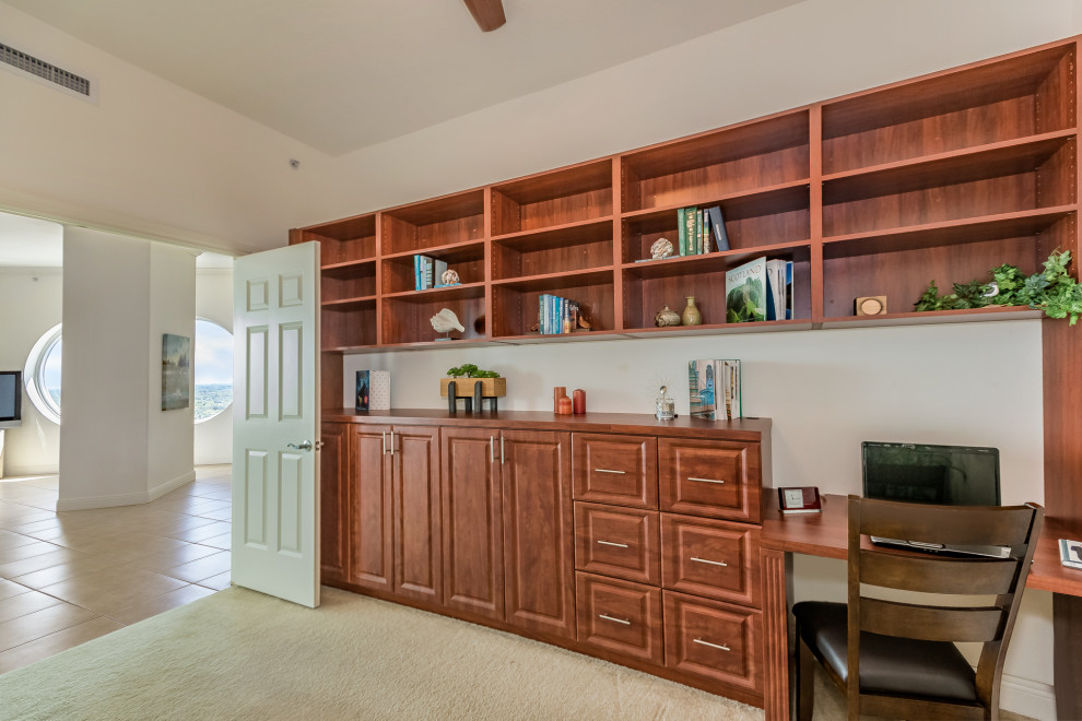 Medium sized modern study in Tampa with white walls, carpet, a built-in desk and beige floors.