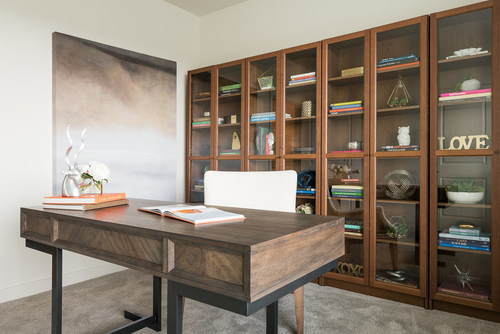 На фото: кабинет в стиле неоклассика (современная классика) с белыми стенами, ковровым покрытием, отдельно стоящим рабочим столом и серым полом