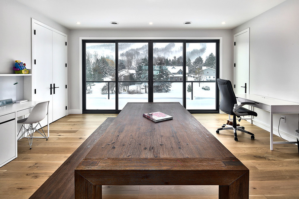 Idee per un grande ufficio minimalista con pareti bianche, pavimento in legno massello medio, scrivania autoportante e pavimento marrone