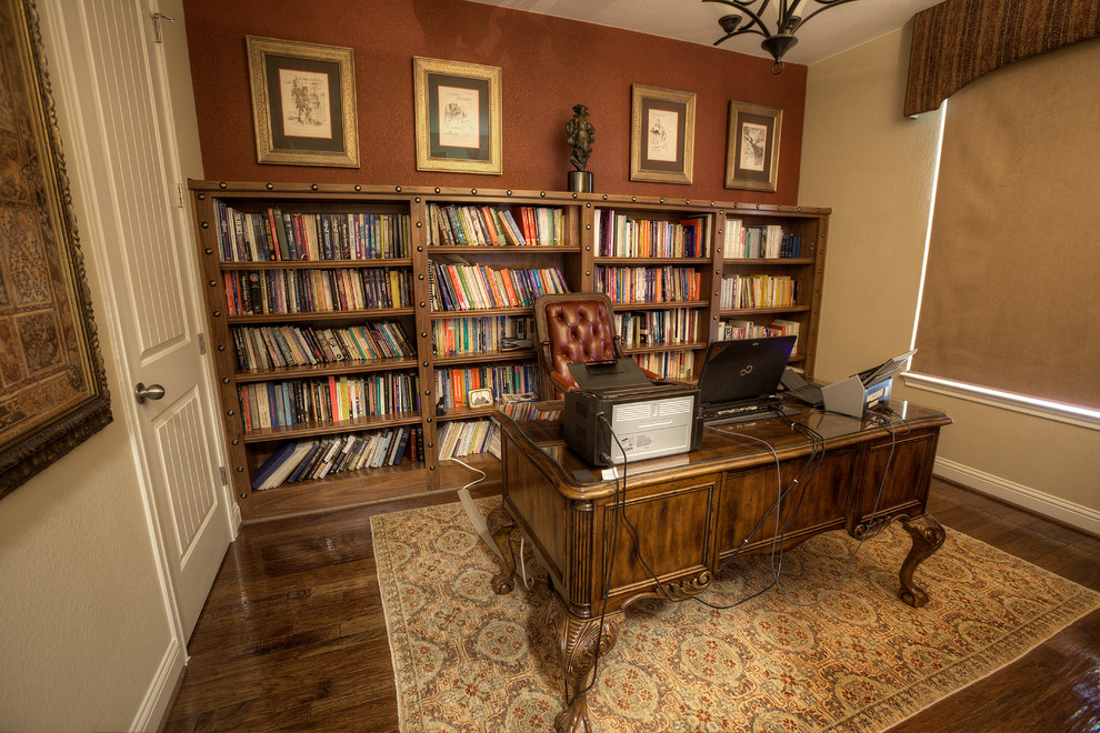 Kleines Klassisches Arbeitszimmer ohne Kamin mit beiger Wandfarbe, braunem Holzboden und freistehendem Schreibtisch in Austin