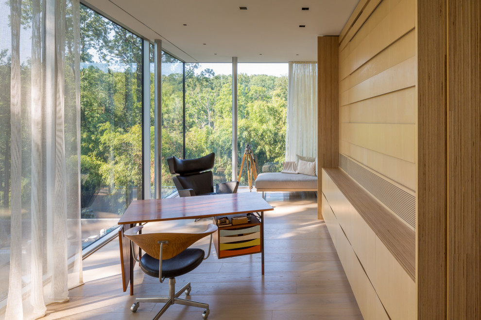 Diseño de despacho minimalista grande con paredes beige, suelo de madera clara, escritorio independiente, suelo beige y madera