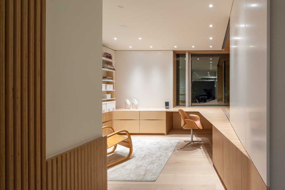 Cette photo montre un bureau moderne avec un mur blanc, parquet clair, un bureau intégré et un sol beige.