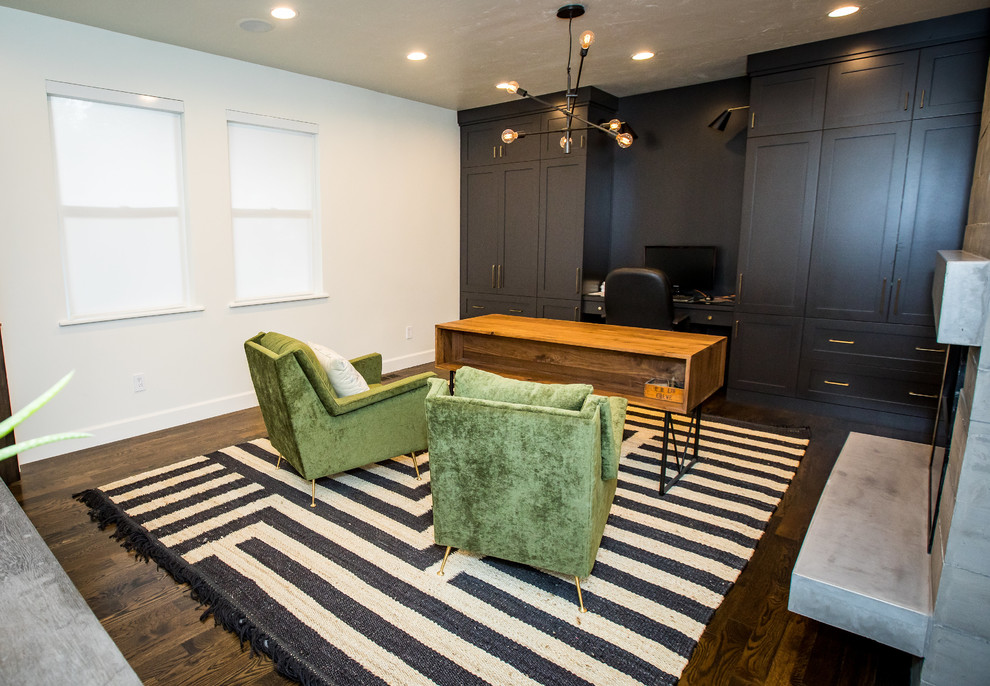 Mittelgroßes Modernes Arbeitszimmer mit weißer Wandfarbe, braunem Holzboden, Kamin, Kaminumrandung aus Beton, freistehendem Schreibtisch und braunem Boden in Salt Lake City