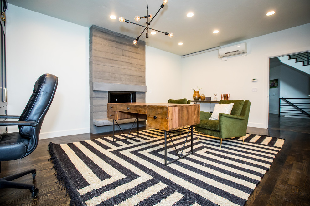 Mittelgroßes Modernes Arbeitszimmer mit weißer Wandfarbe, braunem Holzboden, Kamin, Kaminumrandung aus Beton, braunem Boden und freistehendem Schreibtisch in Salt Lake City