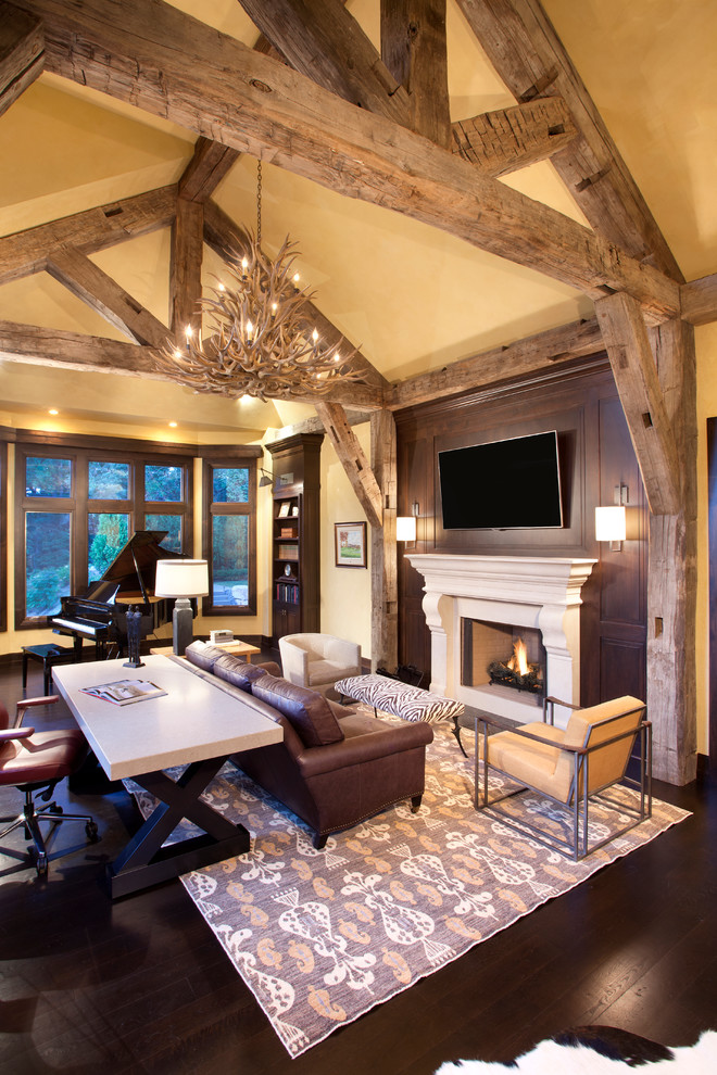 Imagen de despacho rural con paredes beige, suelo de madera oscura, todas las chimeneas, marco de chimenea de piedra y escritorio independiente