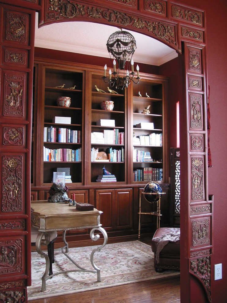 На фото: домашняя библиотека среднего размера в восточном стиле с красными стенами, паркетным полом среднего тона и отдельно стоящим рабочим столом с
