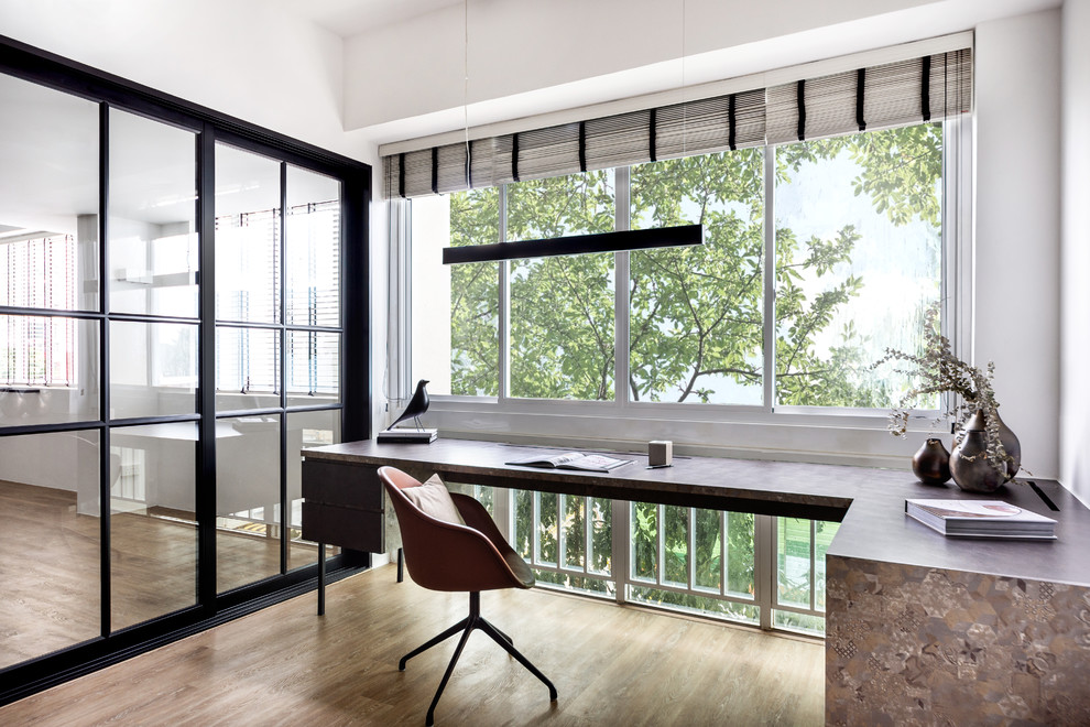 Cette image montre un bureau design avec un mur blanc, un sol en bois brun, un bureau intégré et un sol marron.