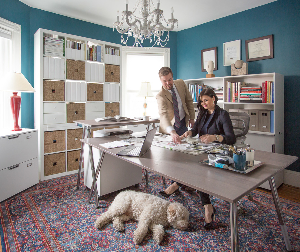 Eklektisk inredning av ett mellanstort hemmabibliotek, med blå väggar, mellanmörkt trägolv och ett fristående skrivbord