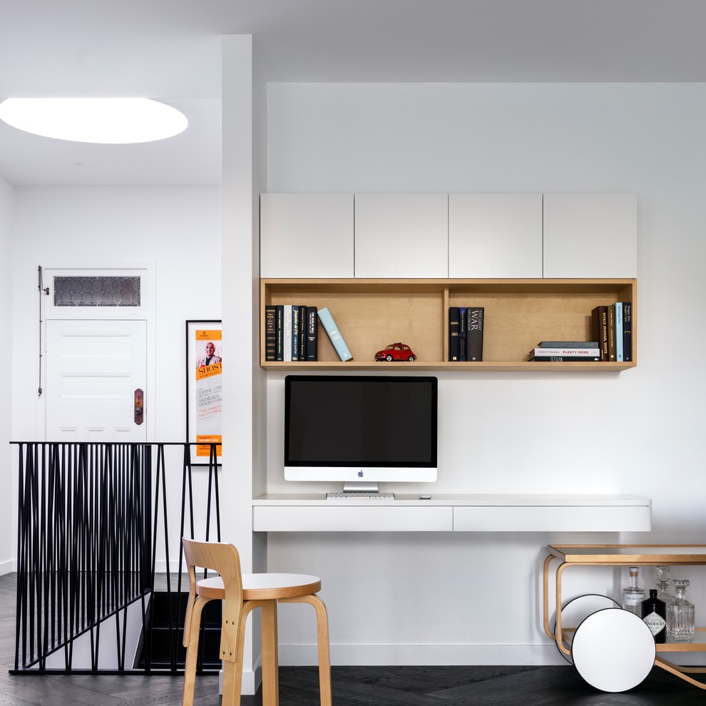 Cette photo montre un bureau scandinave avec un mur blanc, un bureau intégré et un sol noir.