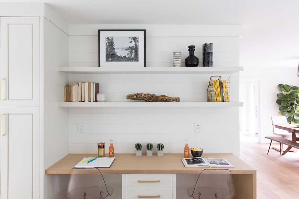 Bild på ett lantligt arbetsrum, med vita väggar, ljust trägolv, ett inbyggt skrivbord och beiget golv