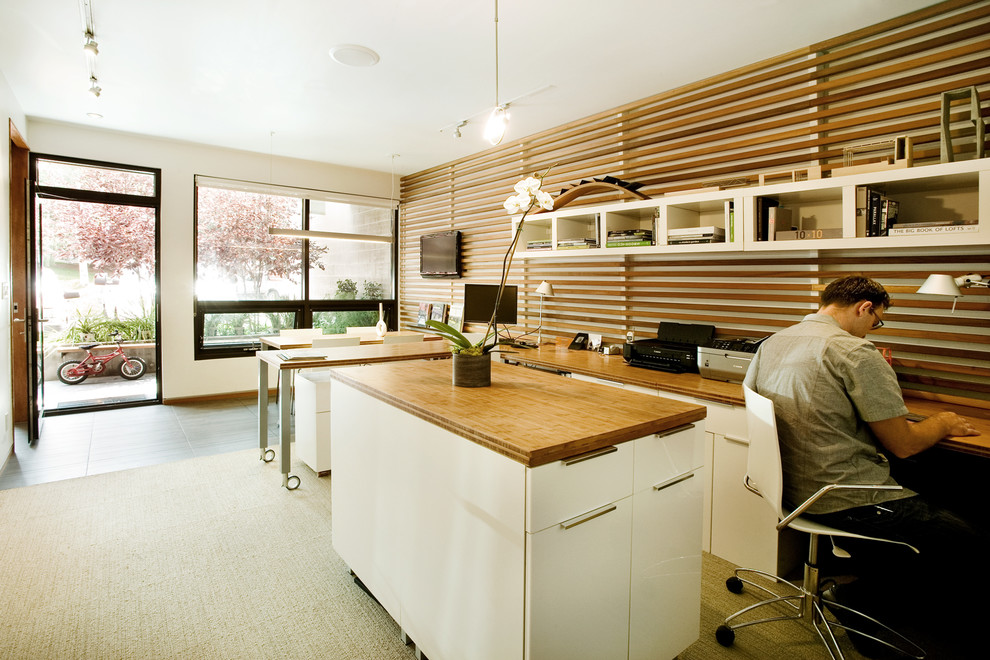 Пример оригинального дизайна: кабинет в стиле модернизм с белыми стенами, ковровым покрытием и встроенным рабочим столом
