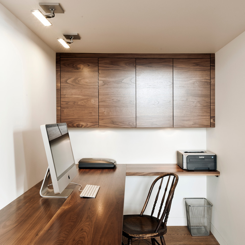 Idéer för ett litet modernt arbetsrum, med vita väggar, mellanmörkt trägolv och ett inbyggt skrivbord