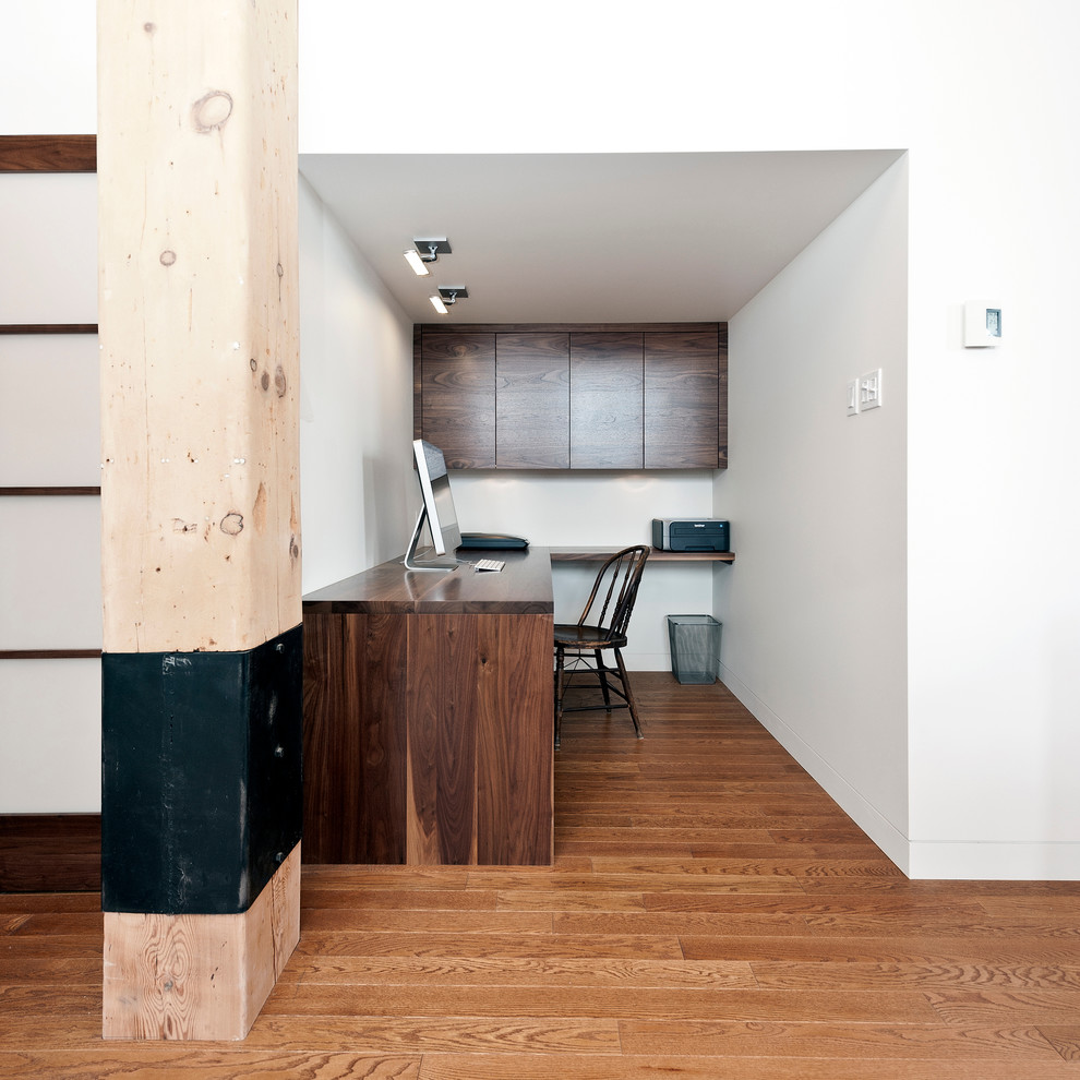 Foto de despacho actual pequeño sin chimenea con paredes blancas, suelo de madera en tonos medios y escritorio empotrado