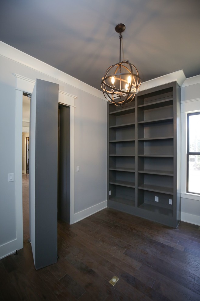 Diseño de despacho clásico renovado de tamaño medio sin chimenea con paredes grises, suelo marrón, biblioteca y suelo de madera oscura