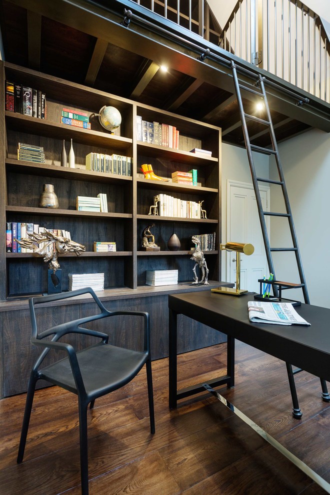 This is an example of a classic study in London with dark hardwood flooring, a freestanding desk and brown floors.