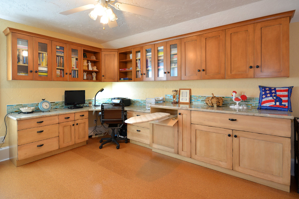 Ejemplo de despacho de estilo de casa de campo de tamaño medio con paredes beige y suelo de corcho