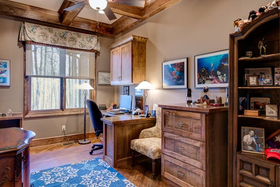 Large rustic study in Other with beige walls, medium hardwood flooring, a built-in desk, no fireplace and brown floors.