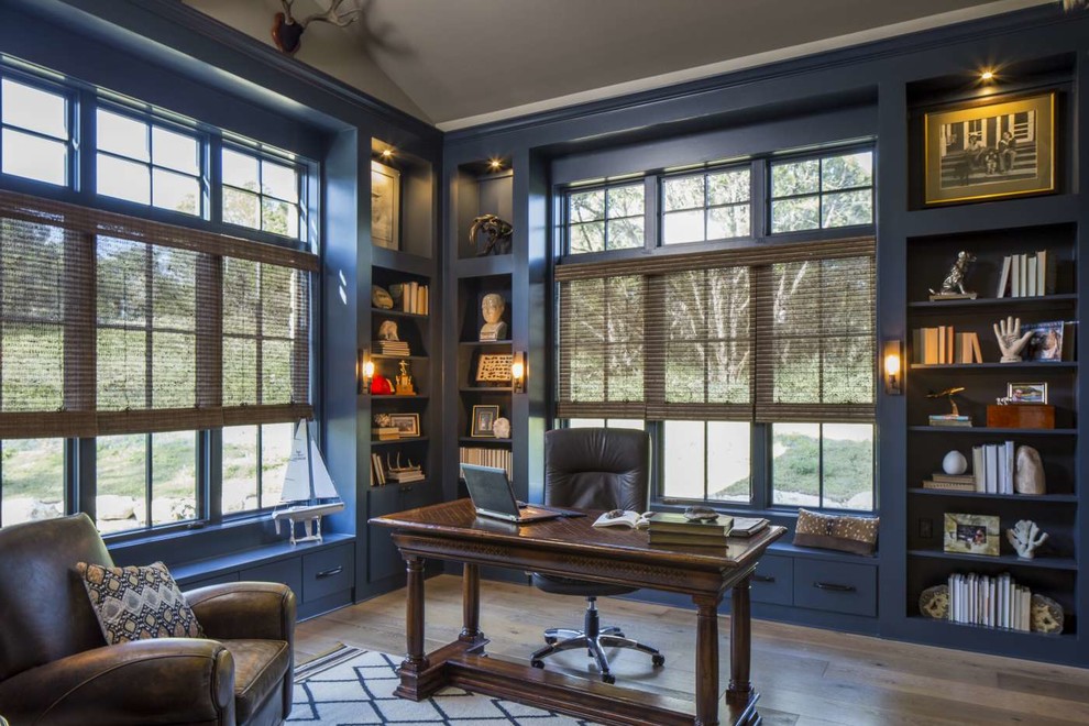 Inredning av ett klassiskt stort hemmabibliotek, med blå väggar, ett fristående skrivbord, brunt golv och ljust trägolv