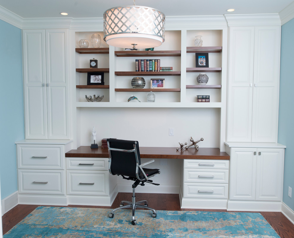 Ejemplo de despacho clásico renovado de tamaño medio con paredes azules, suelo de madera en tonos medios y escritorio empotrado