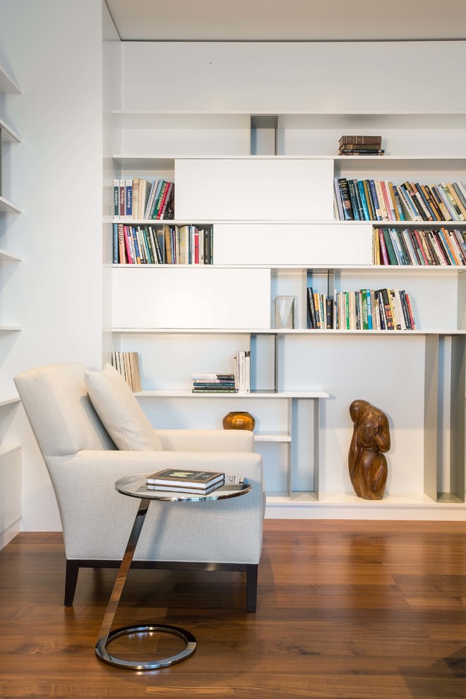 Exemple d'un bureau moderne de taille moyenne avec une bibliothèque ou un coin lecture, un mur blanc, un sol en bois brun, aucune cheminée et un sol marron.