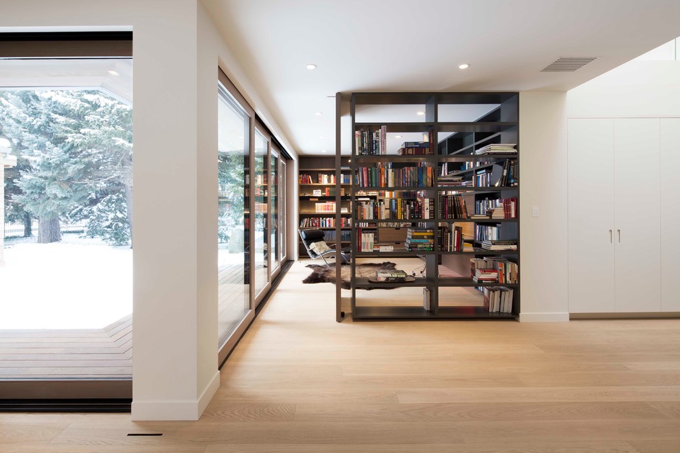 This is an example of a large modern home office in Salt Lake City with a reading nook, white walls, light hardwood flooring, brown floors, a freestanding desk and no fireplace.