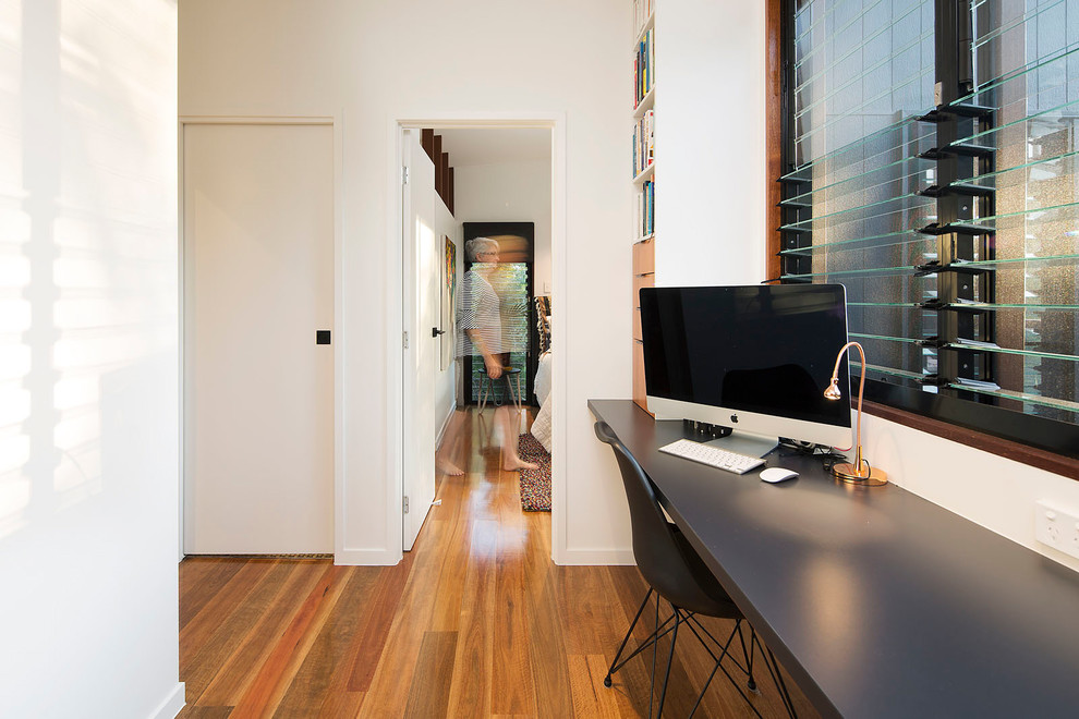 Foto di un piccolo studio moderno con pareti bianche, pavimento in legno massello medio, scrivania incassata e pavimento multicolore