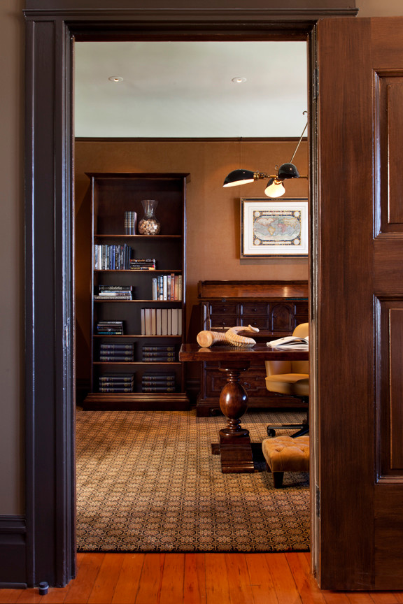 Immagine di un grande ufficio classico con pareti marroni, moquette e scrivania autoportante