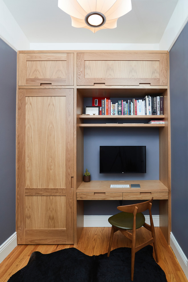 Exemple d'un petit bureau rétro avec un sol en bois brun, un bureau intégré, un mur bleu et un sol marron.