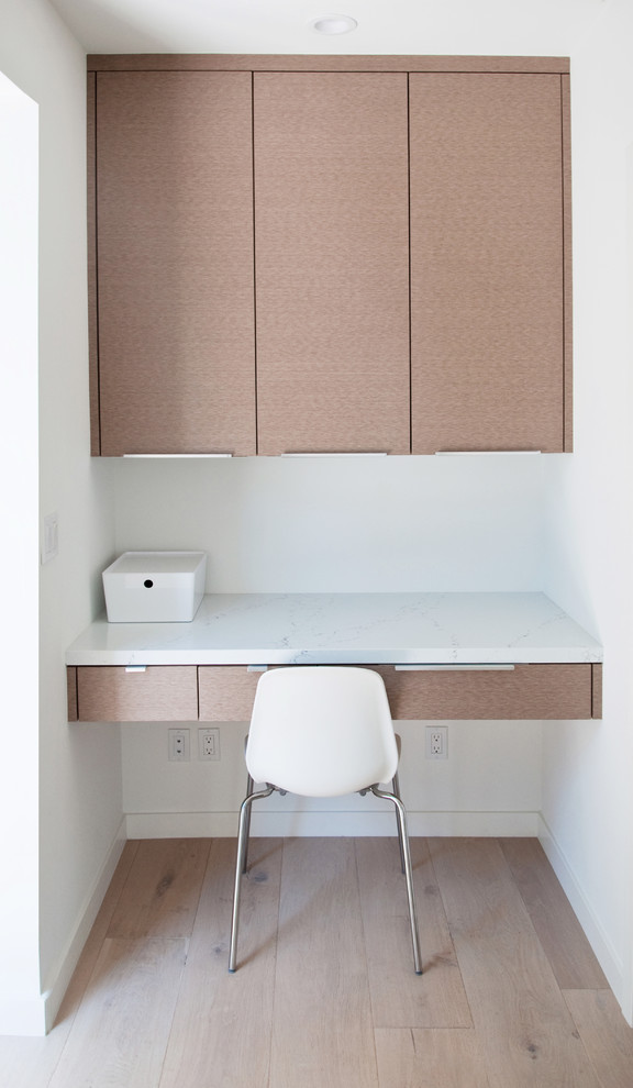 Idee per un piccolo studio moderno con pareti bianche, parquet chiaro, scrivania incassata e pavimento marrone