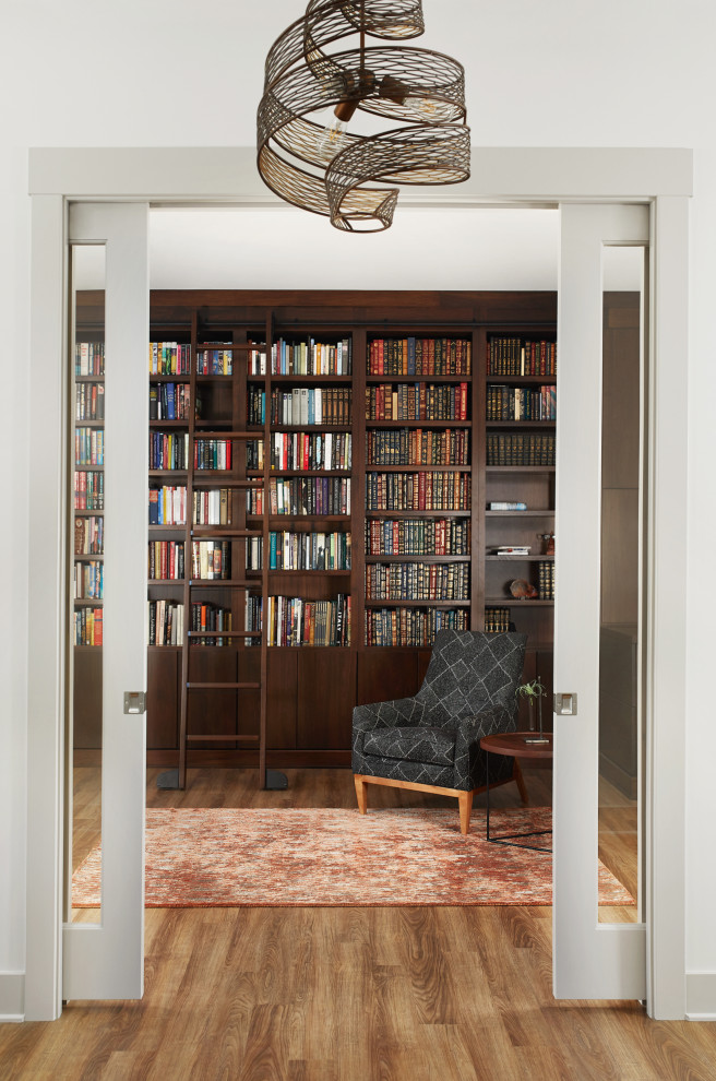 Idée de décoration pour un grand bureau tradition avec une bibliothèque ou un coin lecture, un mur marron, un sol en bois brun et un sol marron.