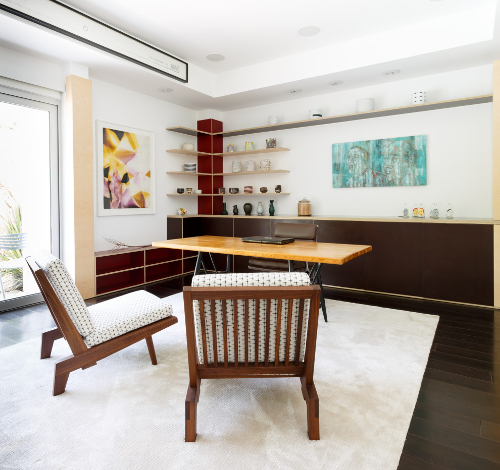 Diseño de despacho contemporáneo con paredes blancas, suelo de madera oscura, escritorio independiente y suelo marrón