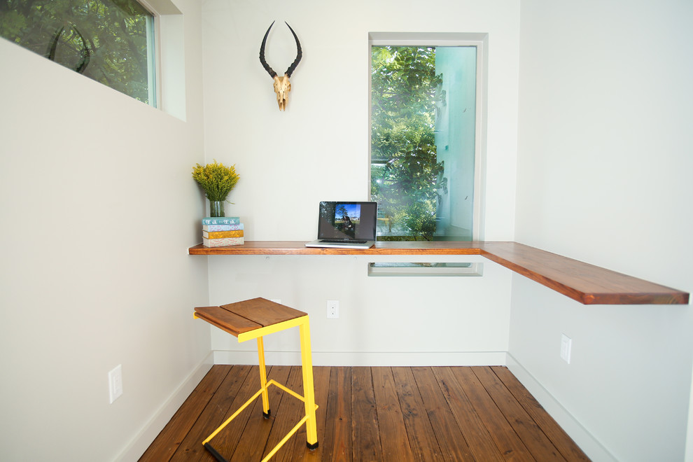 Cette photo montre un petit bureau tendance avec un mur blanc, un sol en bois brun et un bureau intégré.