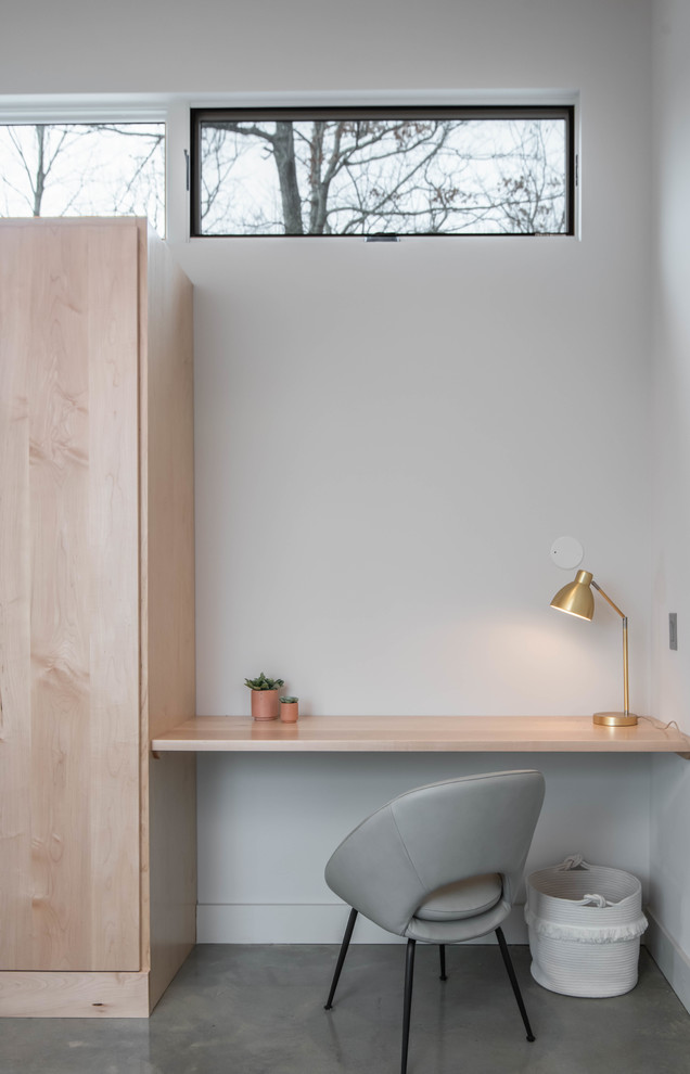 Modelo de despacho escandinavo pequeño con paredes blancas, suelo de cemento, escritorio empotrado y suelo gris