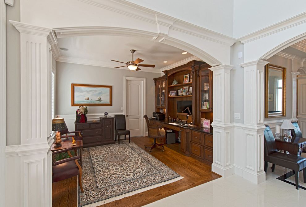 Foto de despacho tradicional de tamaño medio con paredes grises, suelo de madera en tonos medios y escritorio empotrado
