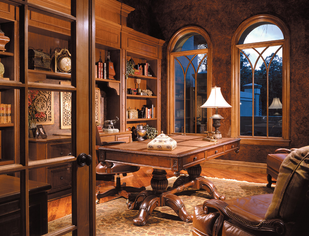 Foto de despacho clásico grande sin chimenea con paredes marrones, suelo de madera en tonos medios y escritorio independiente