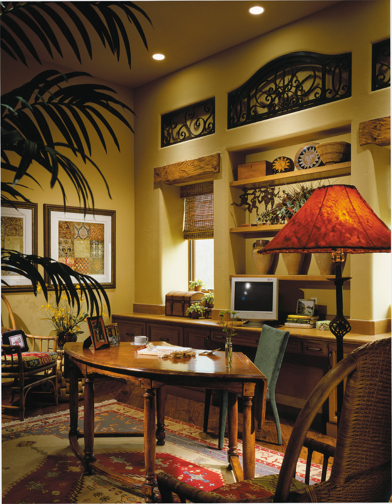 Großes Mediterranes Arbeitszimmer ohne Kamin mit Arbeitsplatz, braunem Holzboden, Einbau-Schreibtisch und gelber Wandfarbe in Miami
