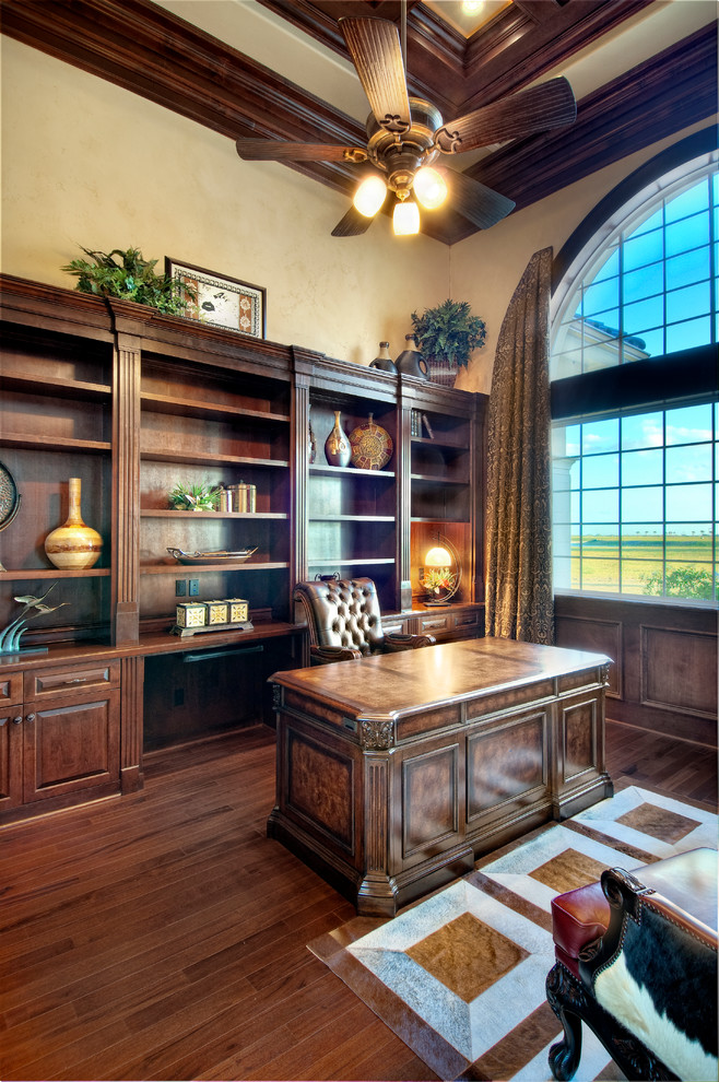 Example of a tuscan freestanding desk dark wood floor home office design in Miami with beige walls