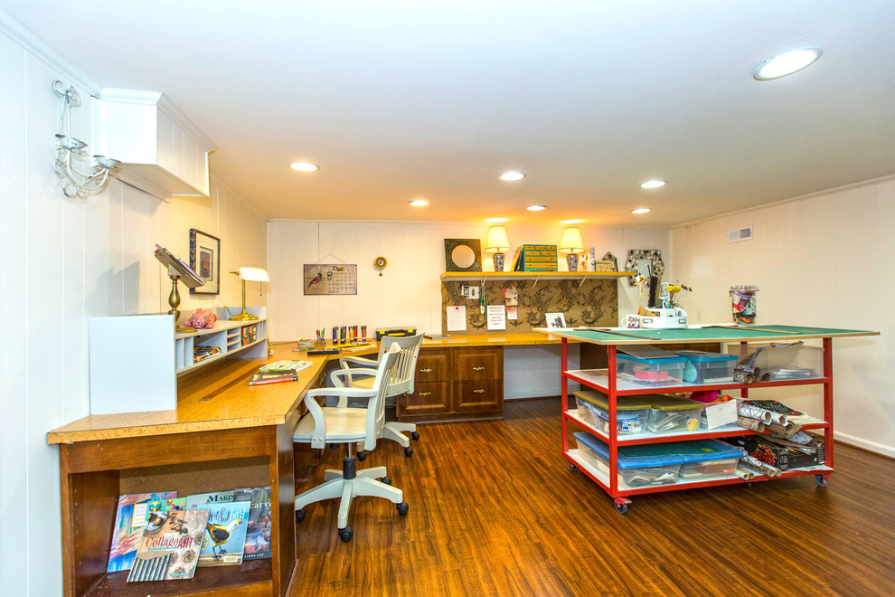 Example of a mid-sized trendy built-in desk medium tone wood floor home studio design in Charlotte with white walls and no fireplace