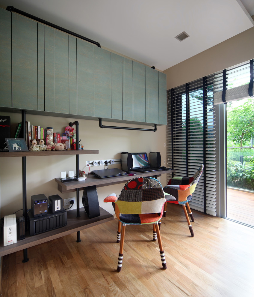 Design ideas for an eclectic study in Singapore with beige walls, light hardwood flooring and a built-in desk.