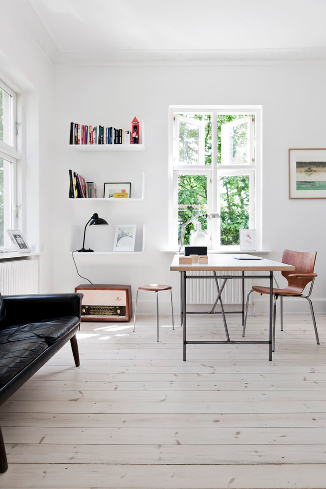 Mittelgroßes Nordisches Arbeitszimmer mit weißer Wandfarbe, hellem Holzboden und freistehendem Schreibtisch in London