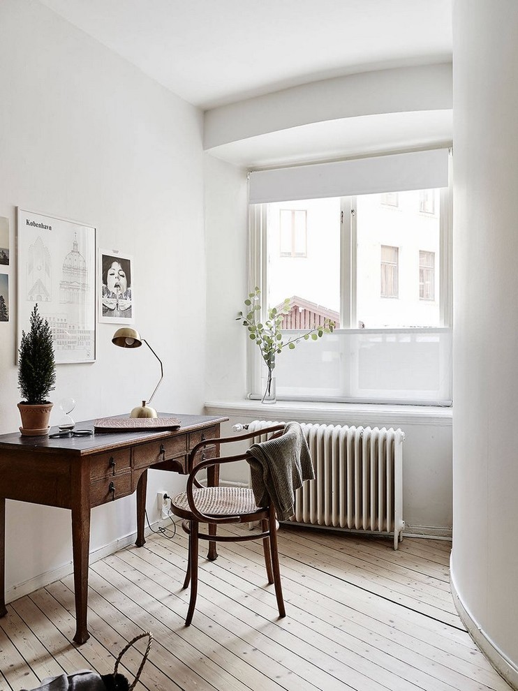 Modelo de despacho escandinavo sin chimenea con paredes blancas, suelo de madera clara y escritorio independiente