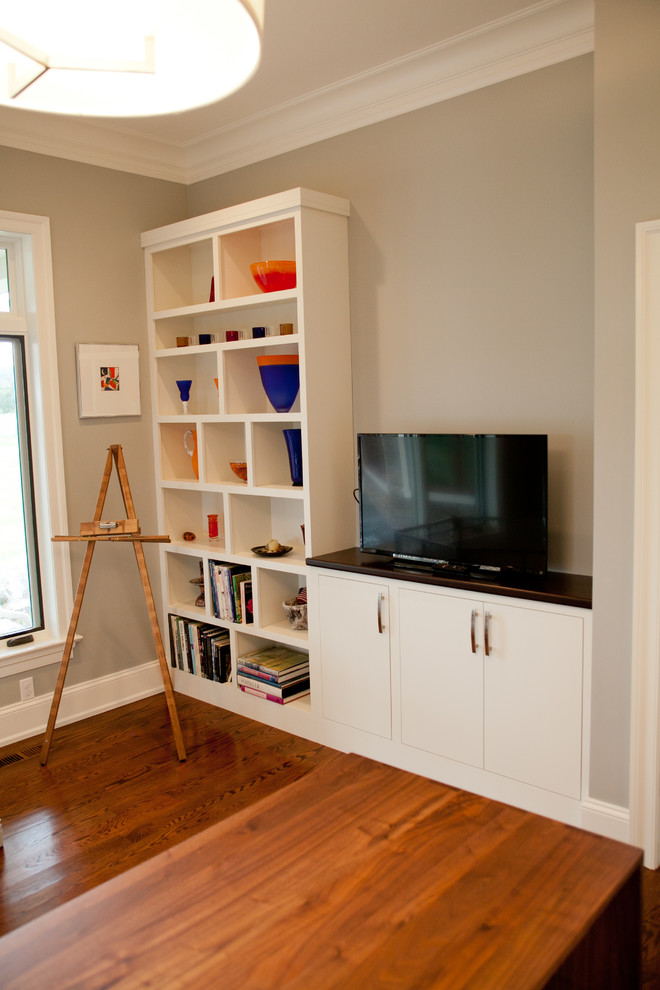 Diseño de despacho actual de tamaño medio sin chimenea con paredes grises, suelo de madera en tonos medios y escritorio independiente