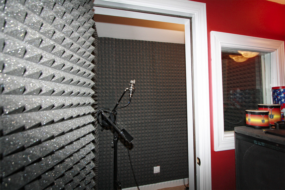 Cette image montre un bureau de type studio avec un mur rouge et moquette.