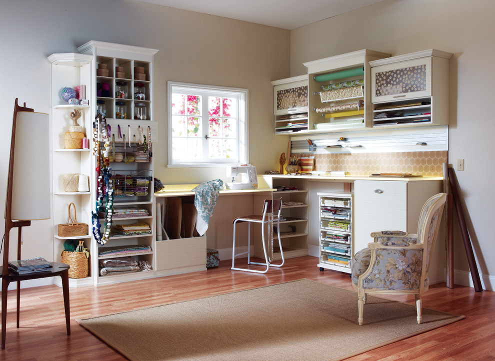 Craft room - mid-sized contemporary built-in desk medium tone wood floor craft room idea in Nashville with beige walls and no fireplace